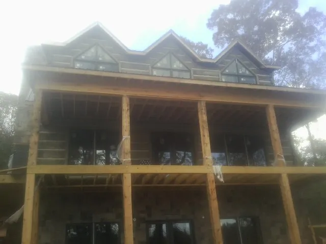 Dormers and porch framing on a large log home under construction — Roof Coating work by our crew in New Orleans