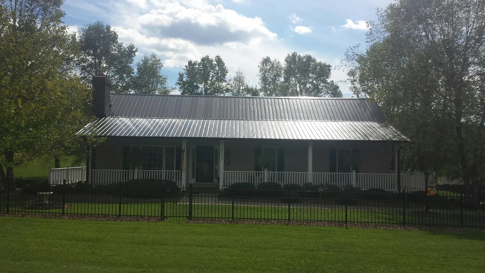 Gray metal roof on a brick ranch with a full width front porch — Gutter Guard Installation work by our crew in New Orleans