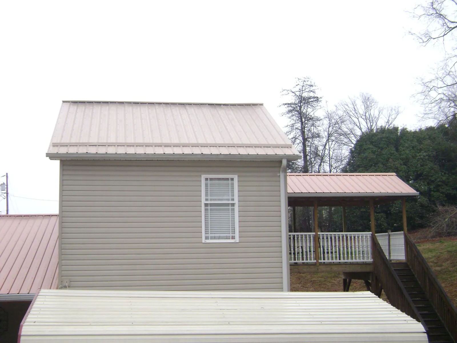 Tan metal roofs on a two story addition and attached porch, from a Roof Replacement job in New Orleans